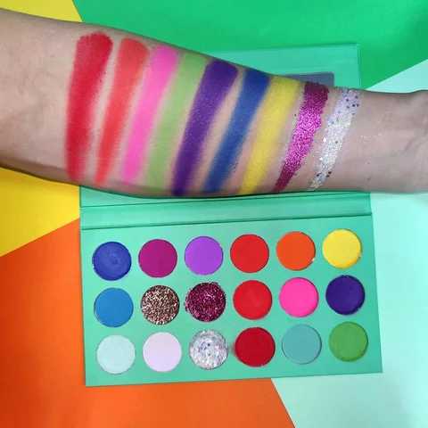 Here, someone has swatched the colors of the palette on their arm. You can see colors Red, Orange, Pink, Green, Purple, Blue, Yellow, Glitter Purple and Glitter white.