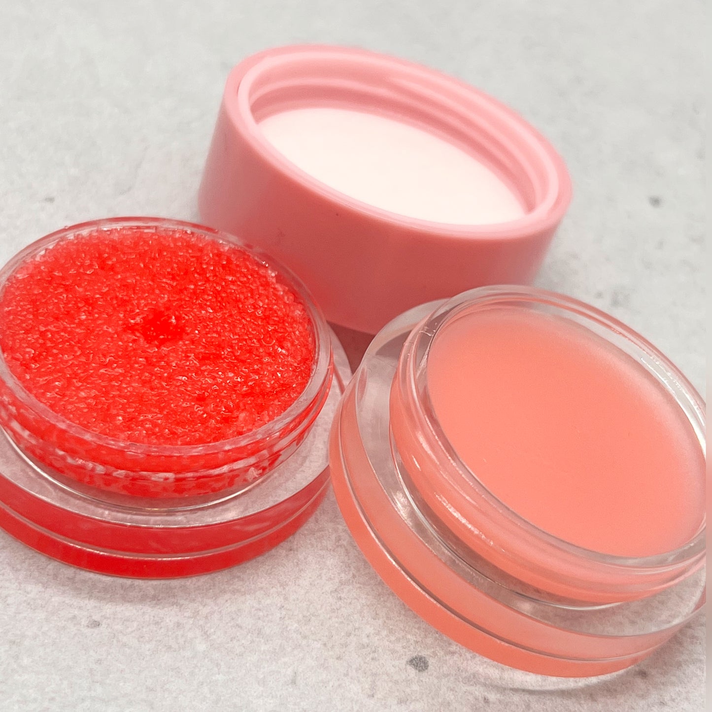 Bold and Luscious Lip Scrub and lip Mask combo up close. on the left, you can see the granulated strawberry scrub in its pot. on the right, you can see the lip mask which is also strawberry.