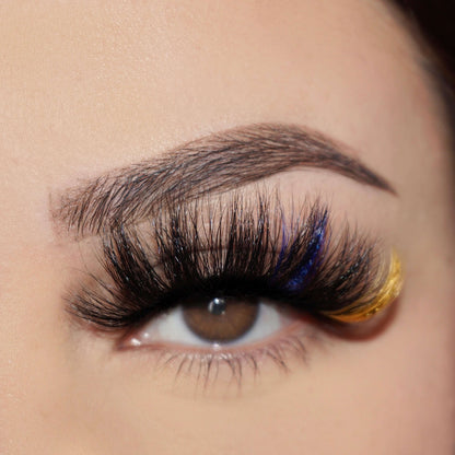 Bold and Luscious Color Splash Lashes in style Samba feature mostly black lashes with a splash of glitter royal blue and glitter yellow towards the outermost corner.