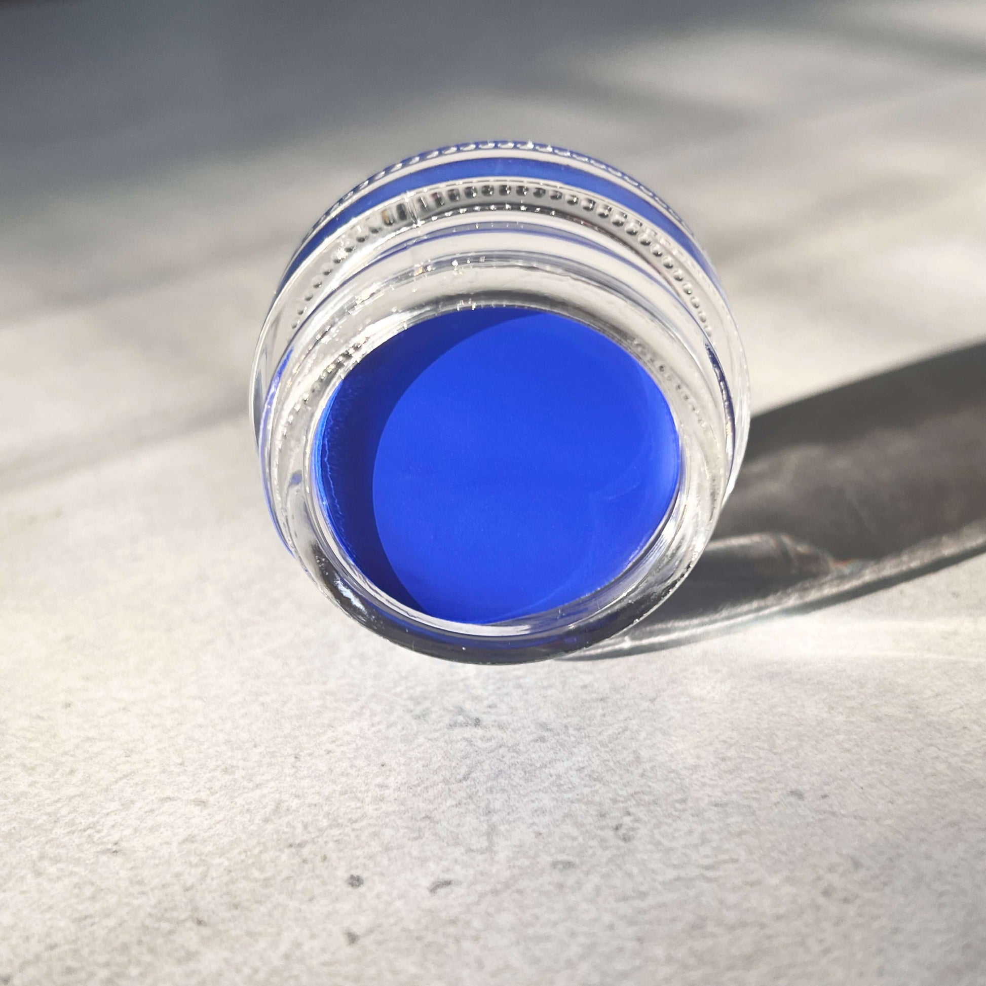 Royal Blue Eyeliner Gel lays on its side within Natural Sunlight.