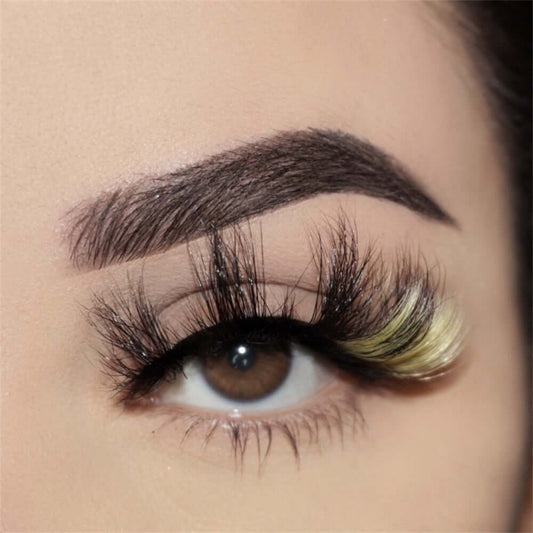 A close up of an eye with an eyebrow features a creative style lash. The Bold and Luscious Cosmetics Lash in style Jadore features yellow lashes on the outer edge of the eye. 
