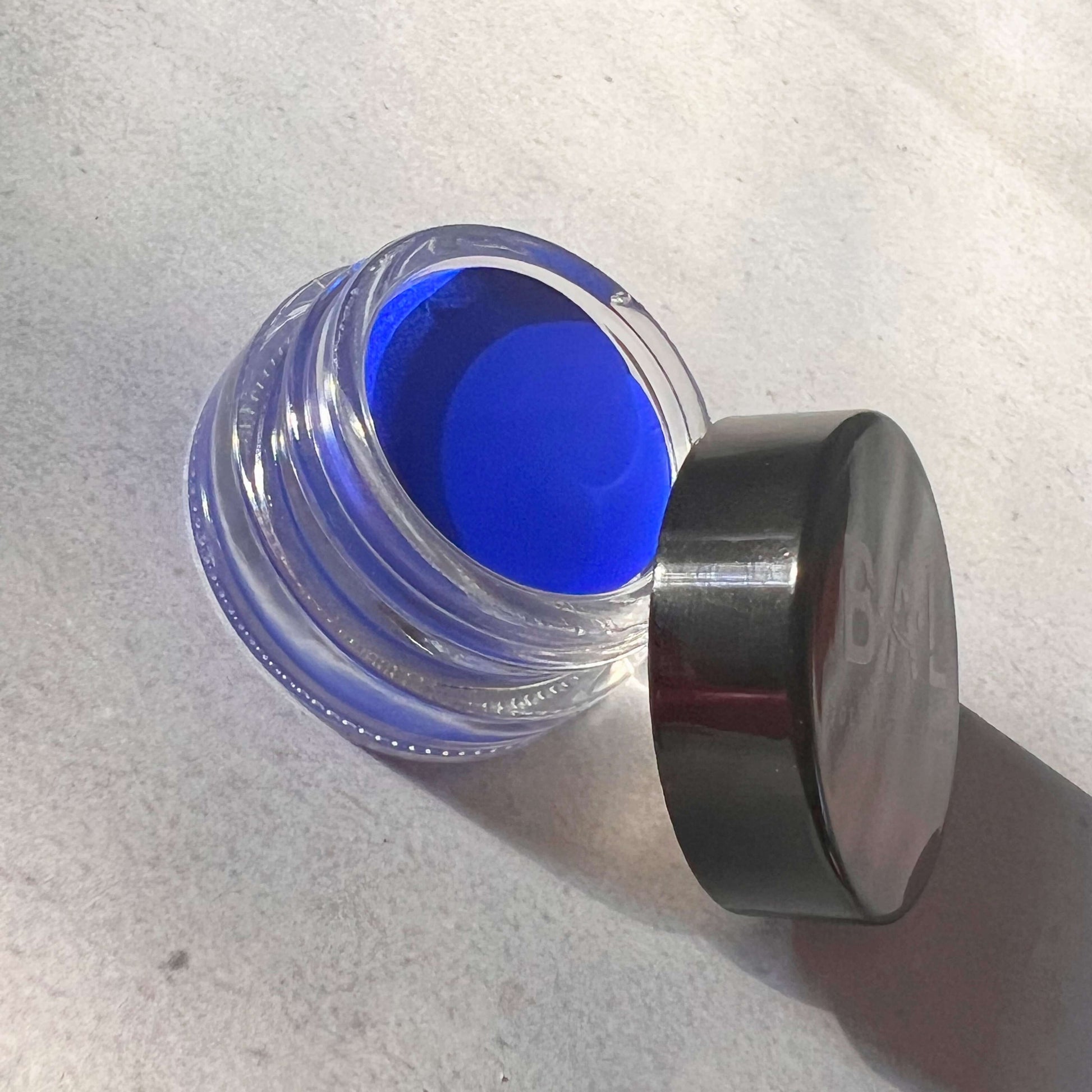 The Lid rests on the side of the blue eyeliner gel pot showing a creamy consistency.