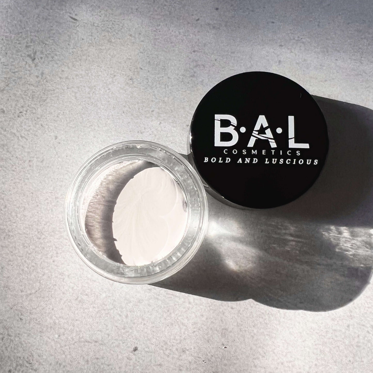 Gel Eyeliner Pot that is White in color inside a glass pot. the Logo for Bold and Luscious Cosmetics is visible on the lid. The texture is soft and creamy.