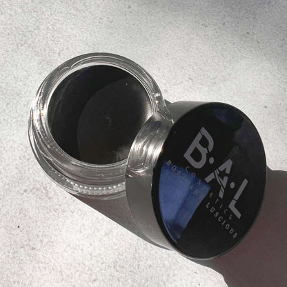 Top View of Gel Eyeliner black in a  glass pot. the Logo for Bold and Luscious Cosmetics is visible on the lid. The texture is soft and creamy.