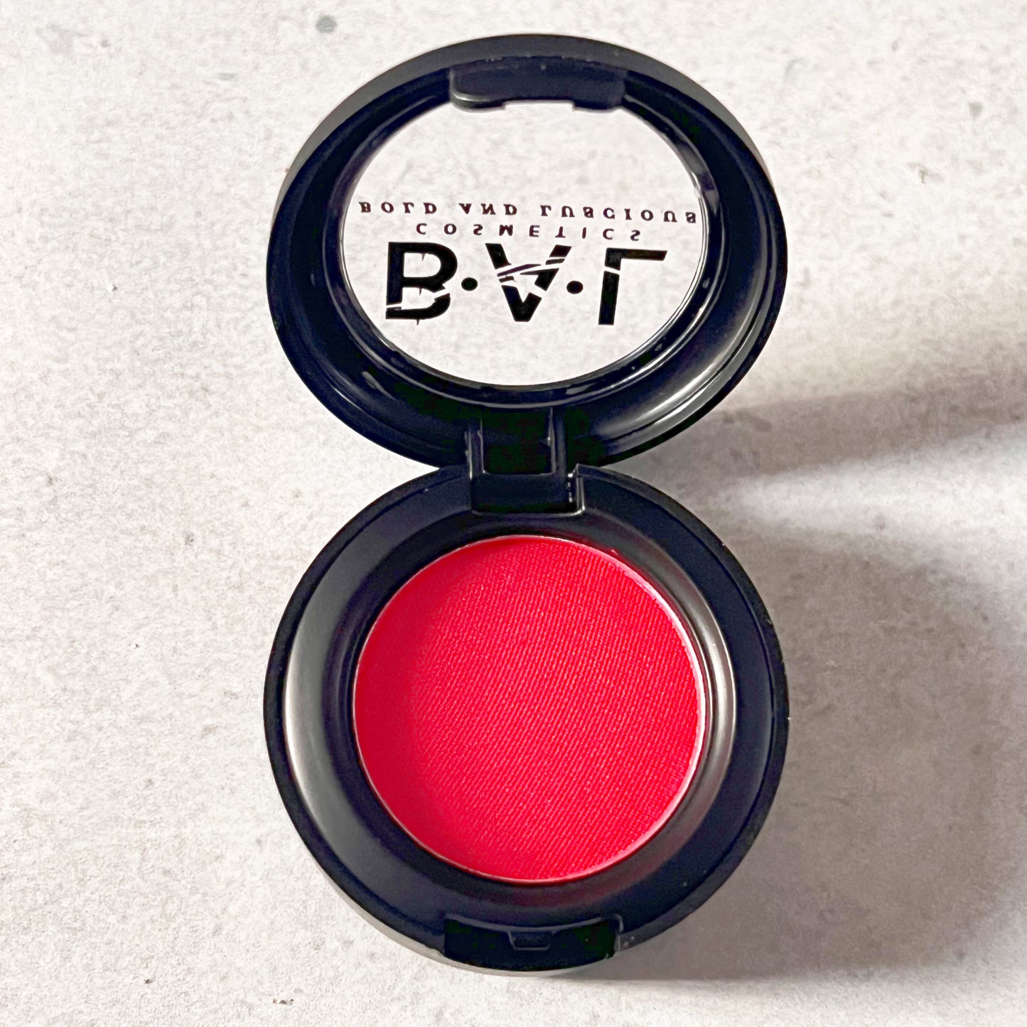 A vibrant shimmery red color in a single pan  by Bold and Luscious Cosmetics.