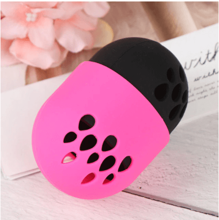 In this picture is a pink and black beauty blender holder. Store your beauty blender in this handy silicone container. it contains ventilation holes to allow your sponge to dry and breathe. Silicone is easy to wipe down and clean. 